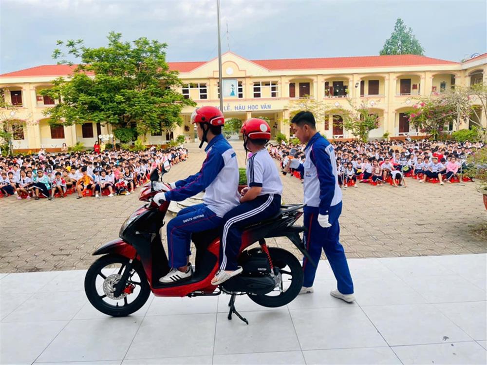 Trao mũ bảo hiểm và hướng dẫn các em cách đội nón đúng cách, ngồi xe khi tham gia giao thông.